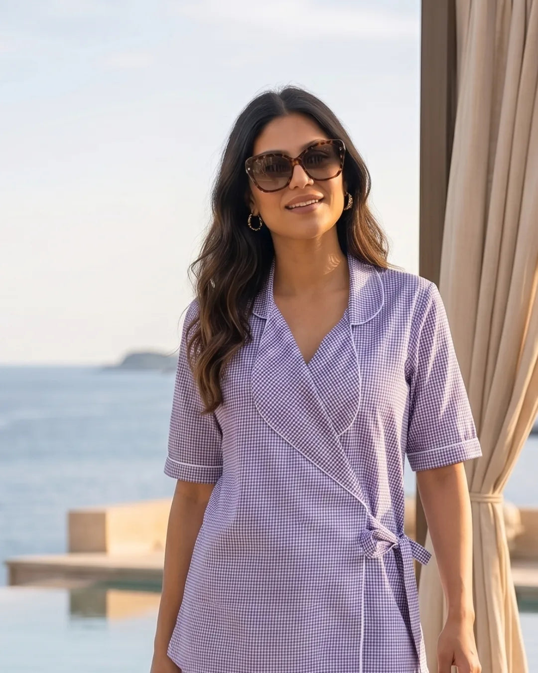 Woman wearing Story Book Wrap Top Wide Leg Trouser Set Piping and sunglasses by a curtain with a scenic background